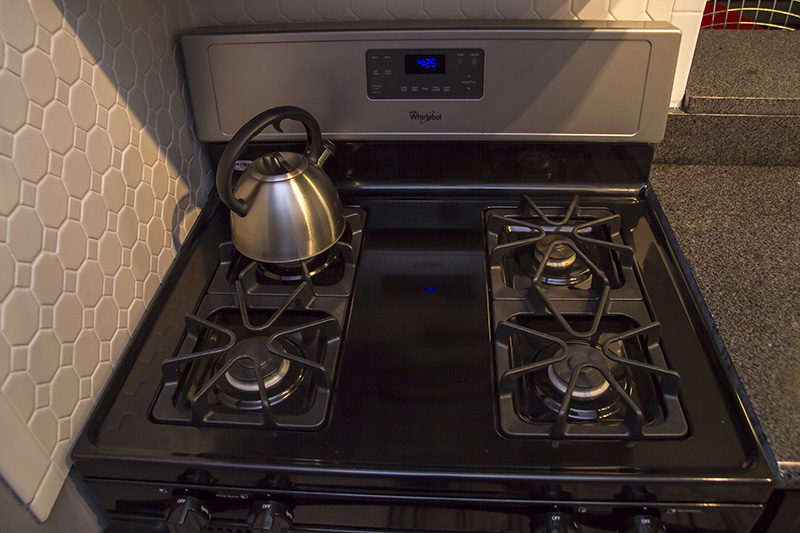 Photo of Gas oven range with 4 burners and a tea kettle on top of the burner